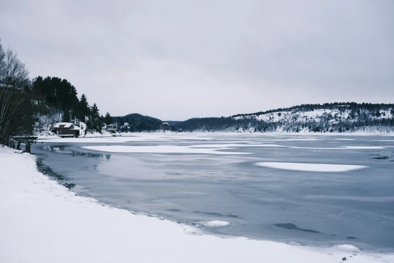 a winter landscape with snow and a frozen lake