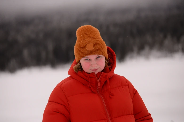 a young child standing in the snow, in front of pine trees