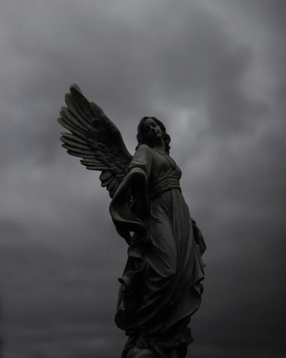 an angel statue holding a cup against a cloudy sky