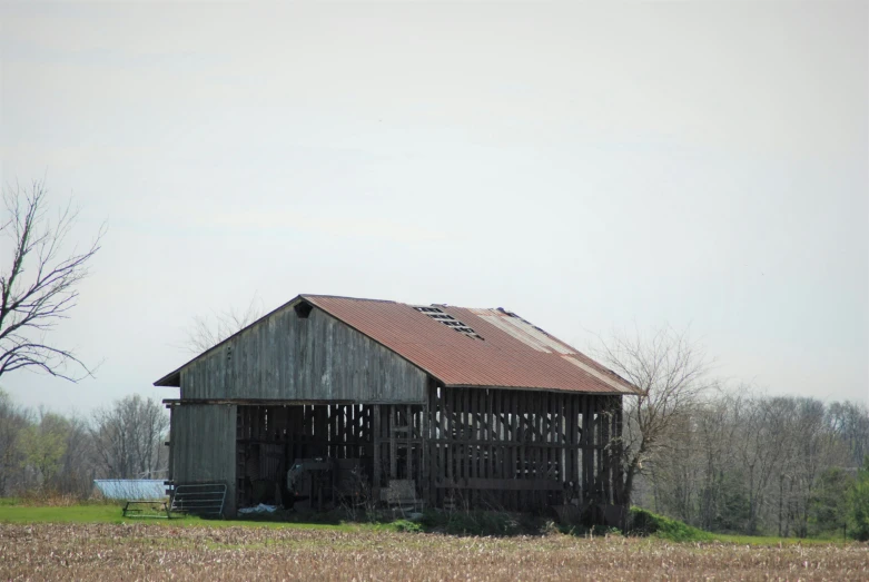 an old barn sits on a farm field