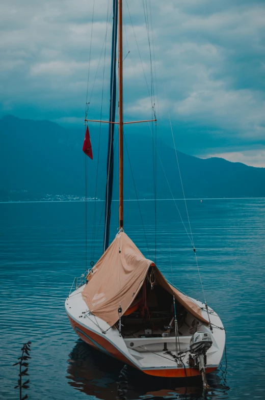 the small sailboat is on the water under the clouds