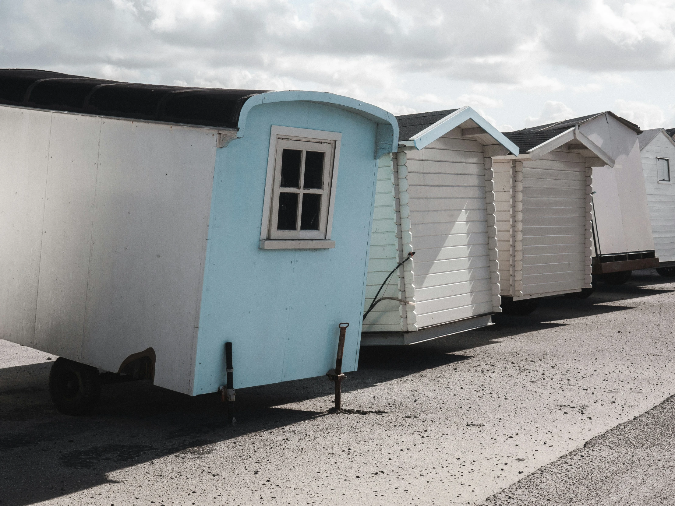 a row of colorful beach huts sitting on top of a gravel road