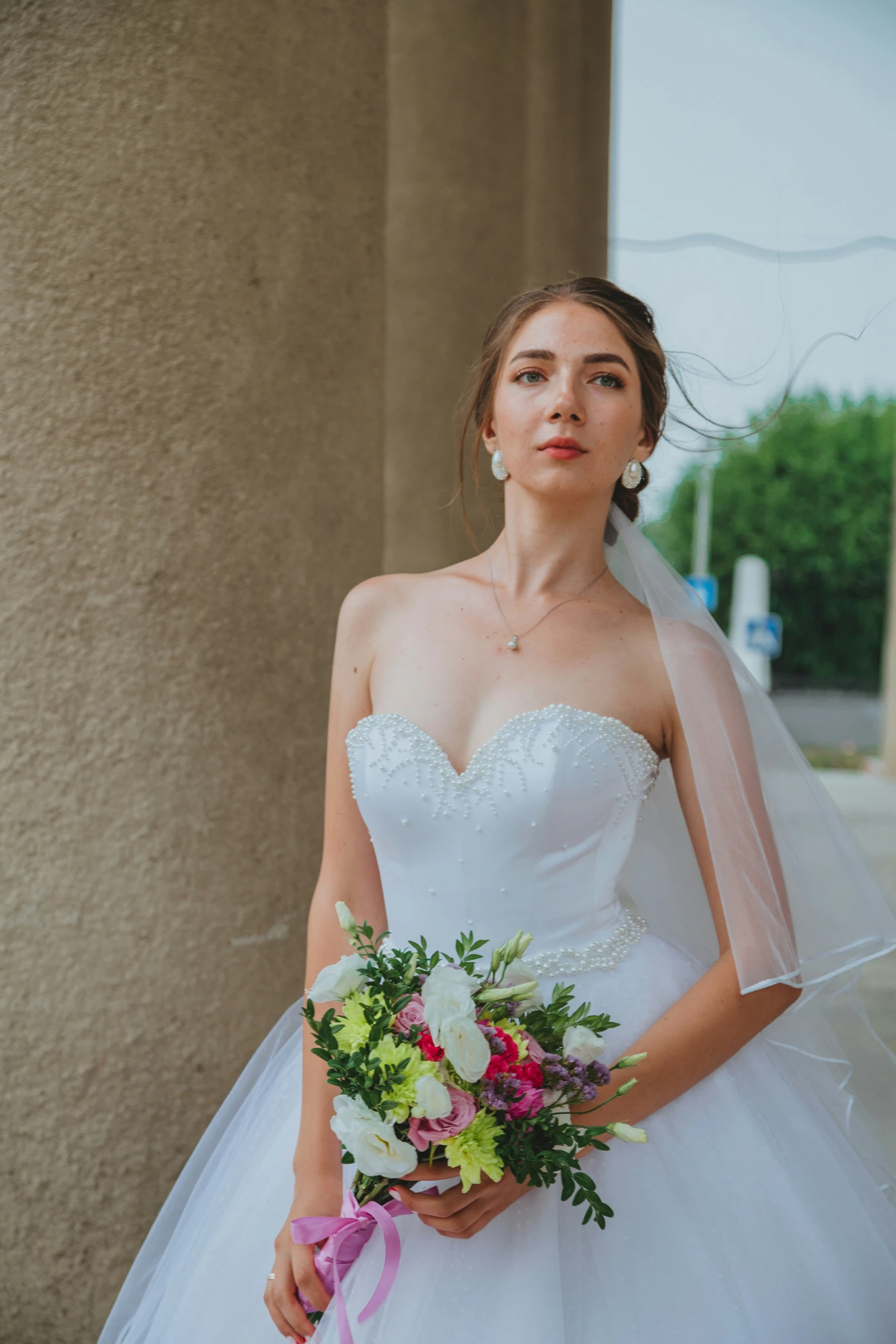 a bride is in front of a building holding her bouquet