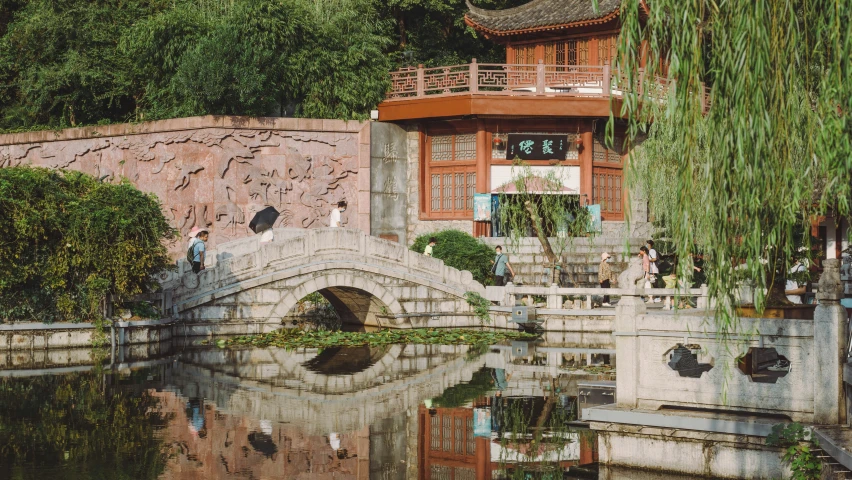 people standing on the steps overlooking a river with a small bridge