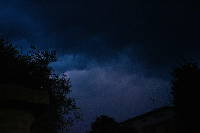 a dark night with buildings and trees and some clouds