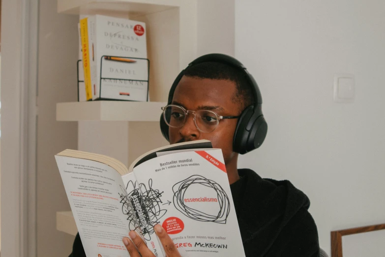 an african american man listening to headphones reading a book