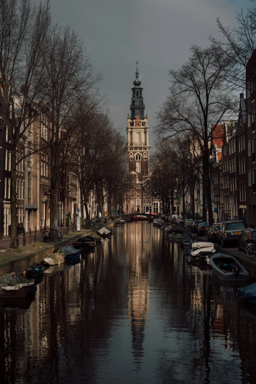 a small canal has a clock tower in the background