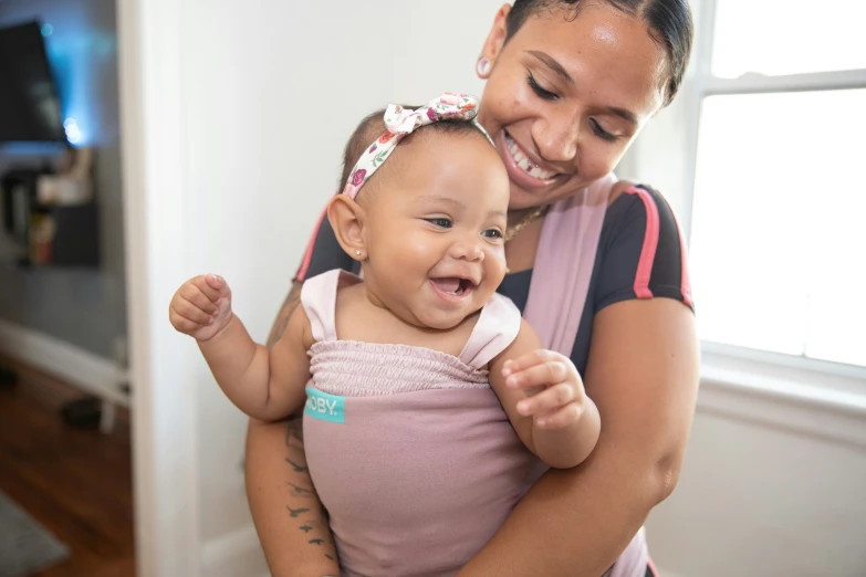 a woman smiles as she holds a small baby