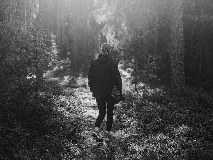 black and white pograph of a person walking through a forest