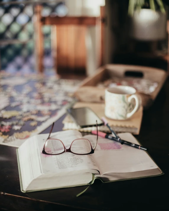 the book is opened on the table near the cup