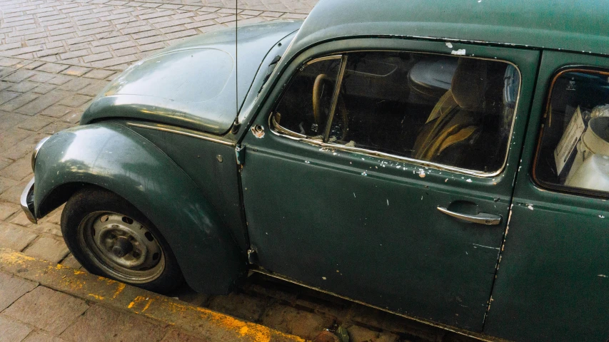 an old, faded green volkswagen beetle with its top window open