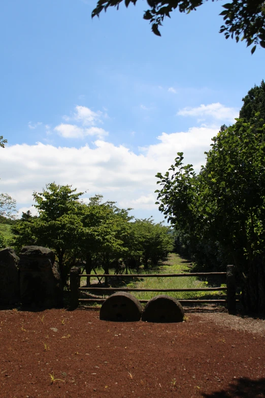 a dirt area has two large boulders and a fence