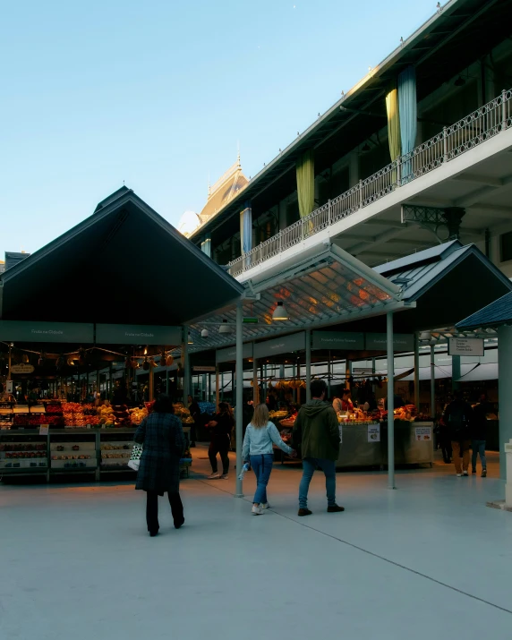 people in a square at dusk with some under canopy covering