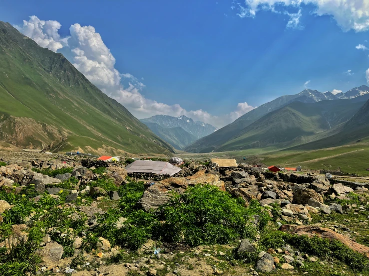 rocky terrain, with several tents in the background