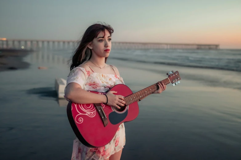 woman with red guitar next to water and pier