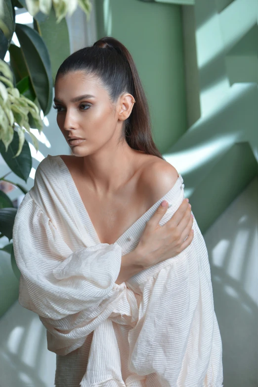 a woman posing in a white dress with a flower arrangement behind her