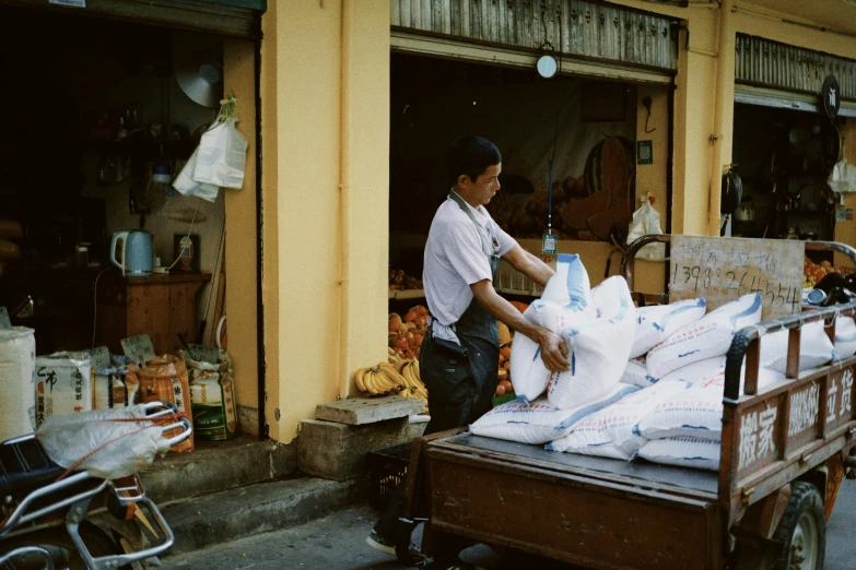 a man in the street loading a cart full of cement bags