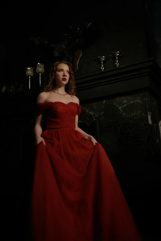 a young woman wearing an elegant dress in a dark room