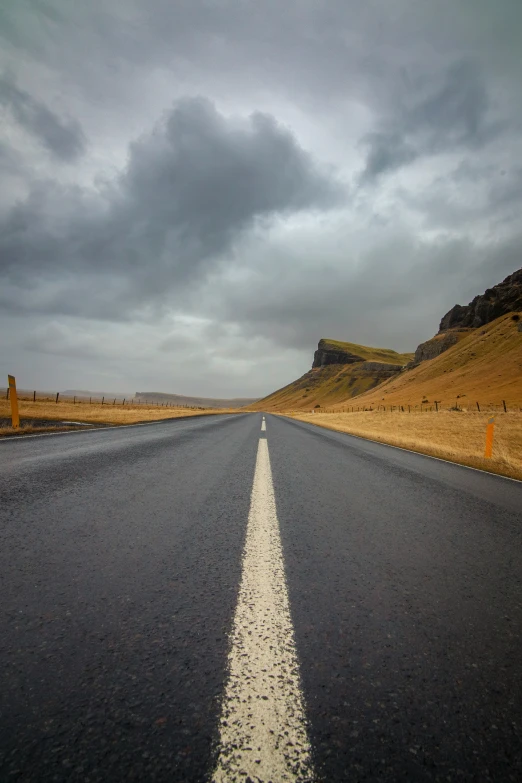 a lonely road with one lone white stripe going through the distance