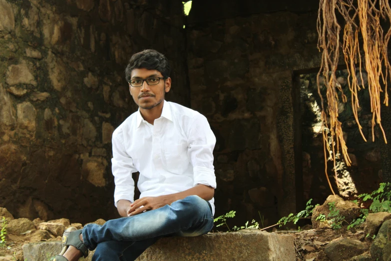 a man is sitting down and wearing jeans