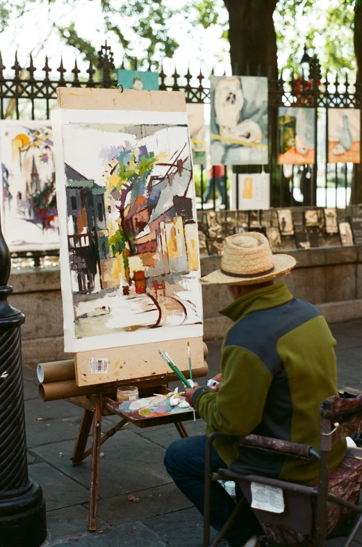 a man sitting in front of an easel painting