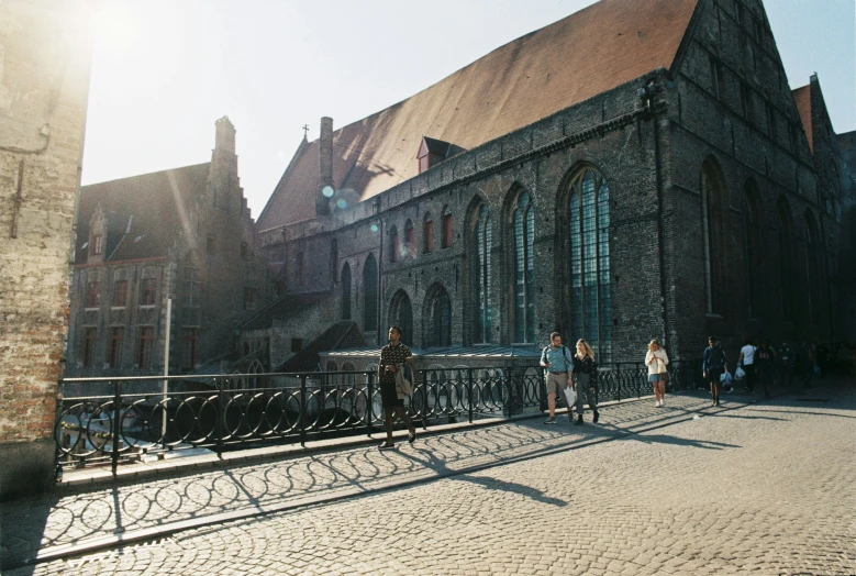 people walking on stone pavement with church behind fence