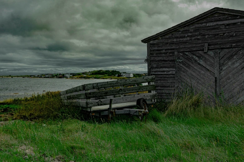 a wooden shack in the field next to the ocean