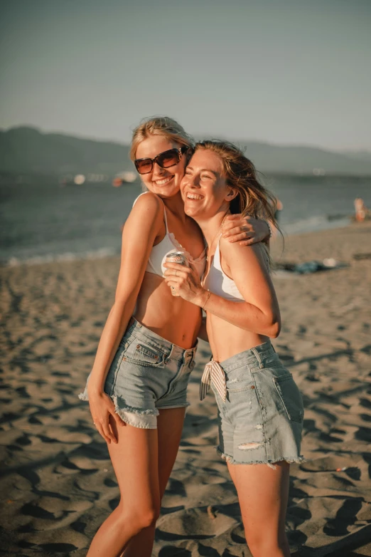 two young women standing on a sandy beach