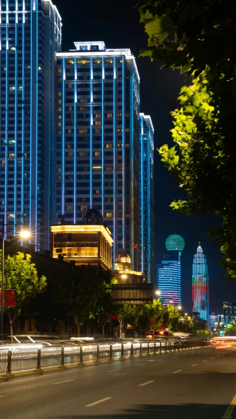 an empty road with illuminated buildings at night