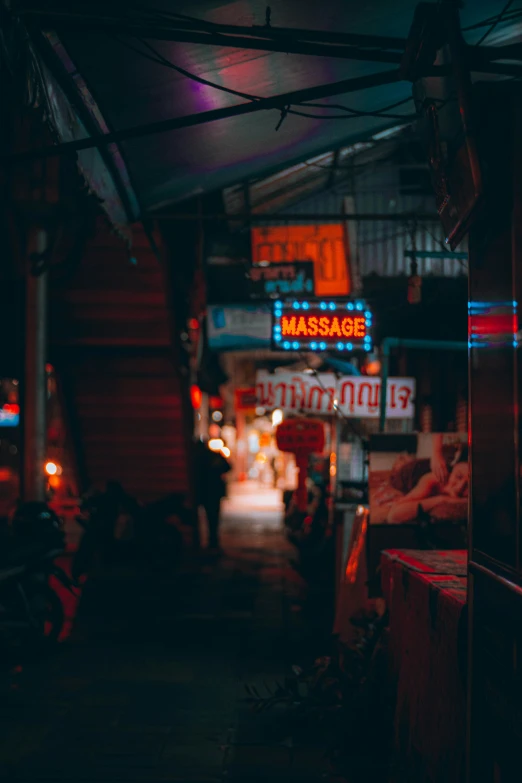 a dark alley with neon lights and business signs