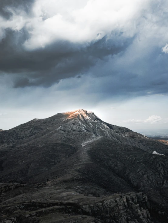 a very tall mountain in the middle of a cloudy sky