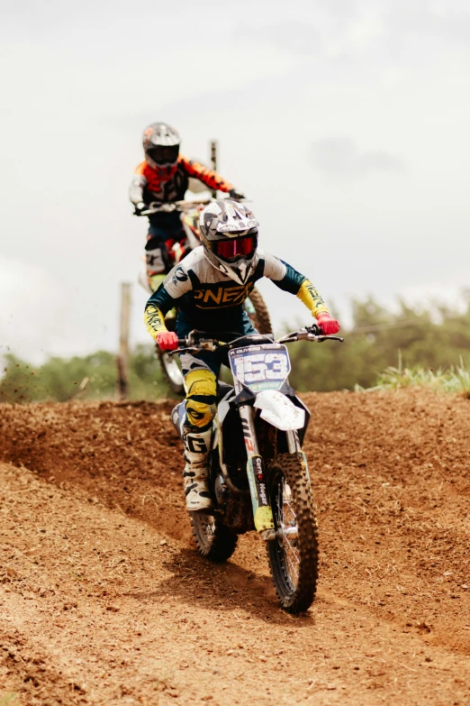 two motocross riders are riding together on the dirt