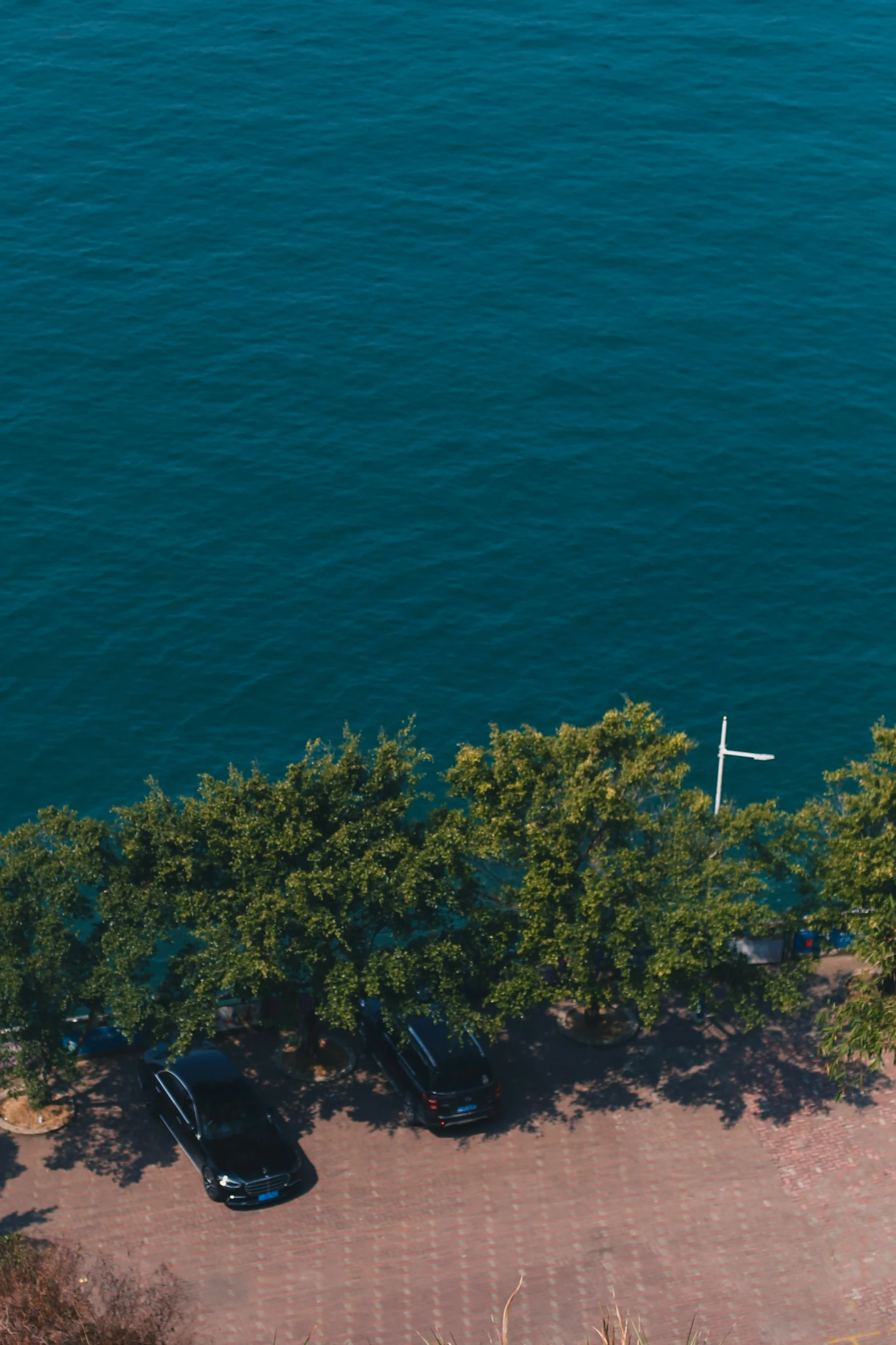 a view of the sea from a height view of three vehicles parked on a concrete platform