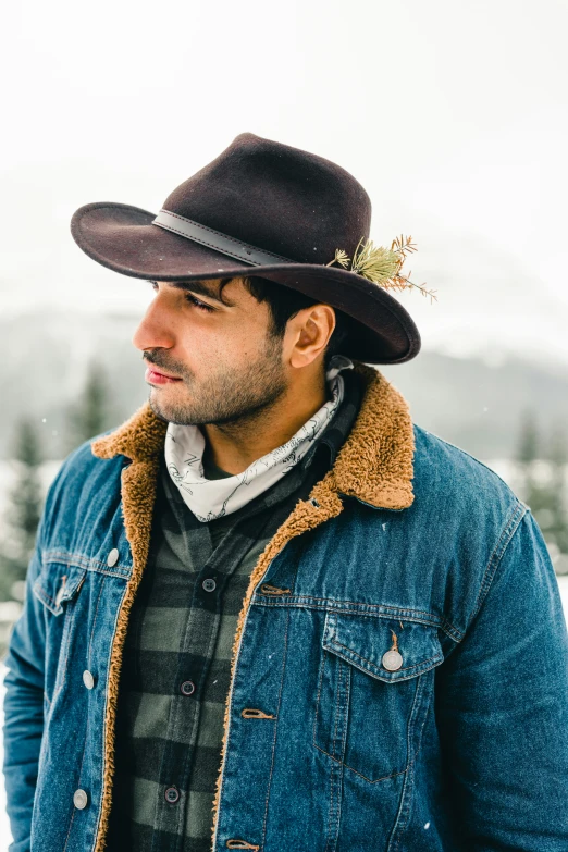 the man is wearing a brown hat and denim jacket