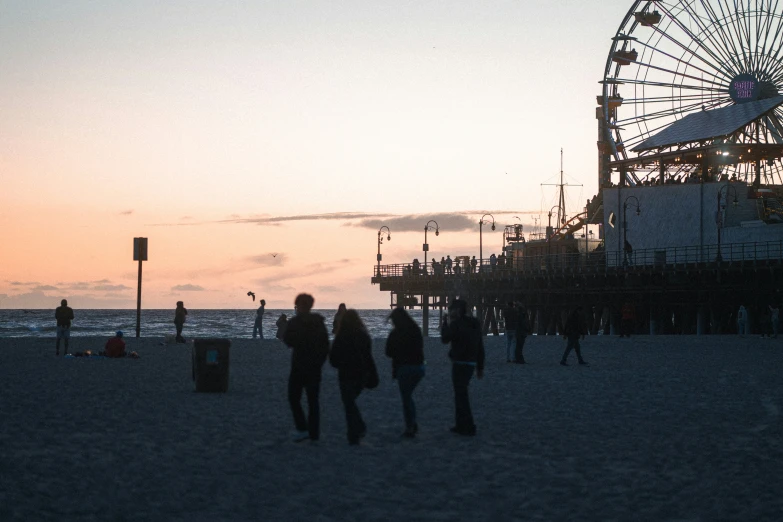 a ferris wheel is shown on the beach at dusk