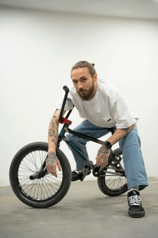 man with piercings kneeling down on a small bicycle