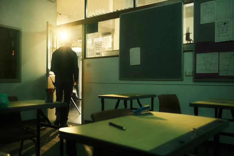 an empty classroom with a man entering into the door
