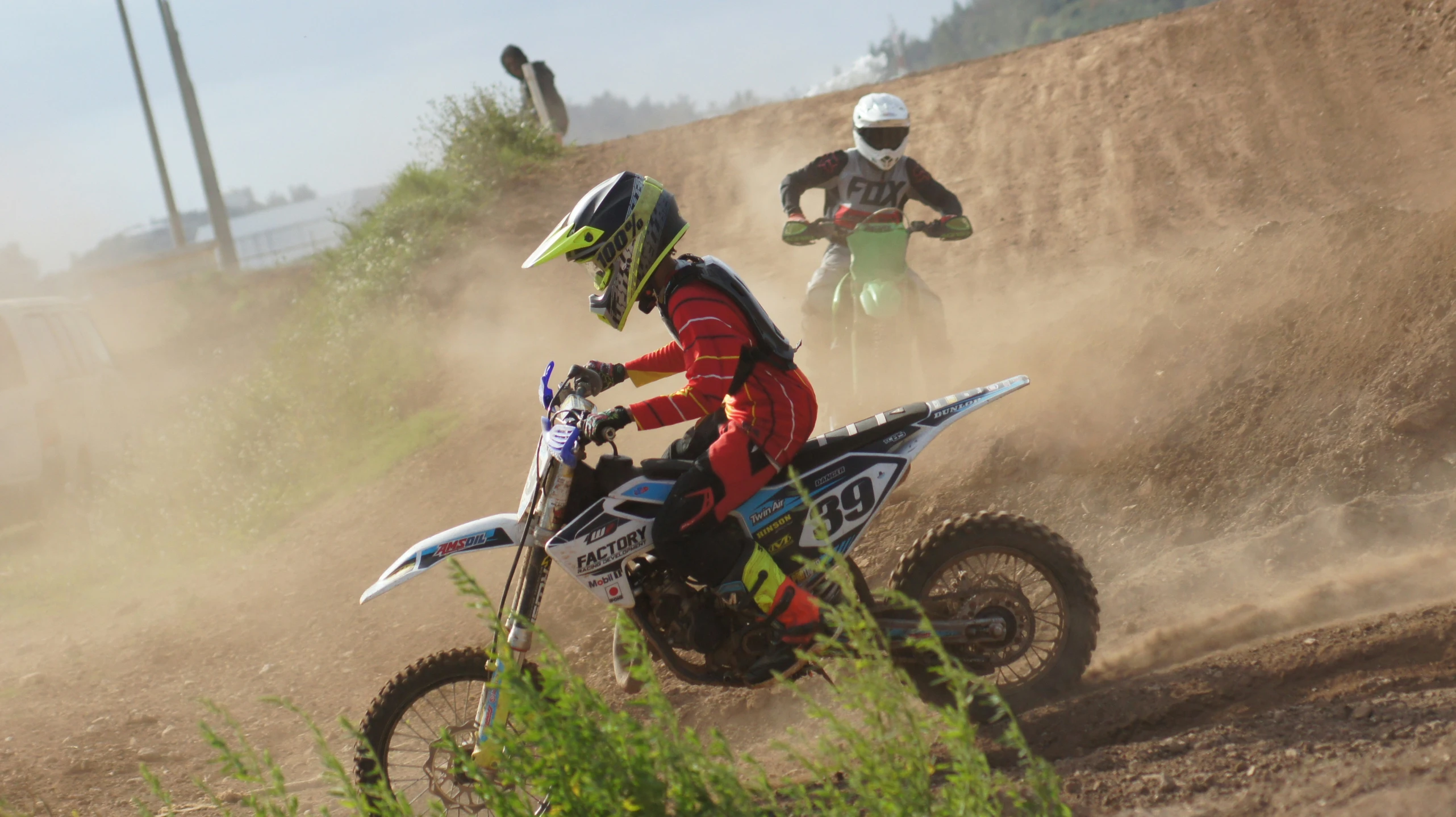 two people riding motorcycles on dirt in a desert