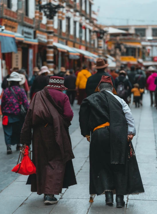 two people wearing dark coats are walking down the street