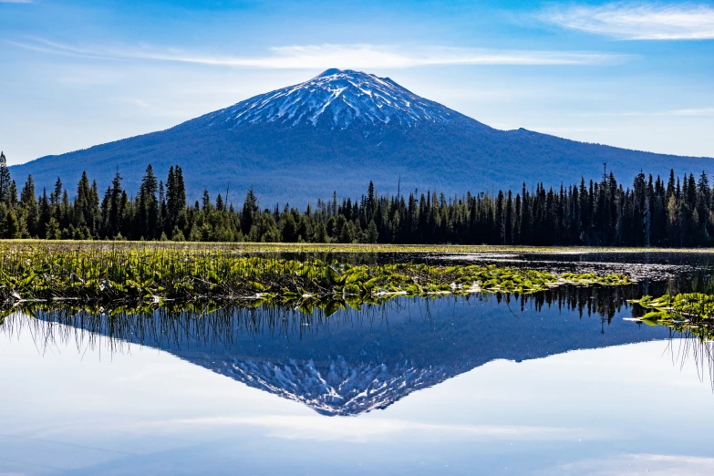 a mountain sitting above water with trees near by