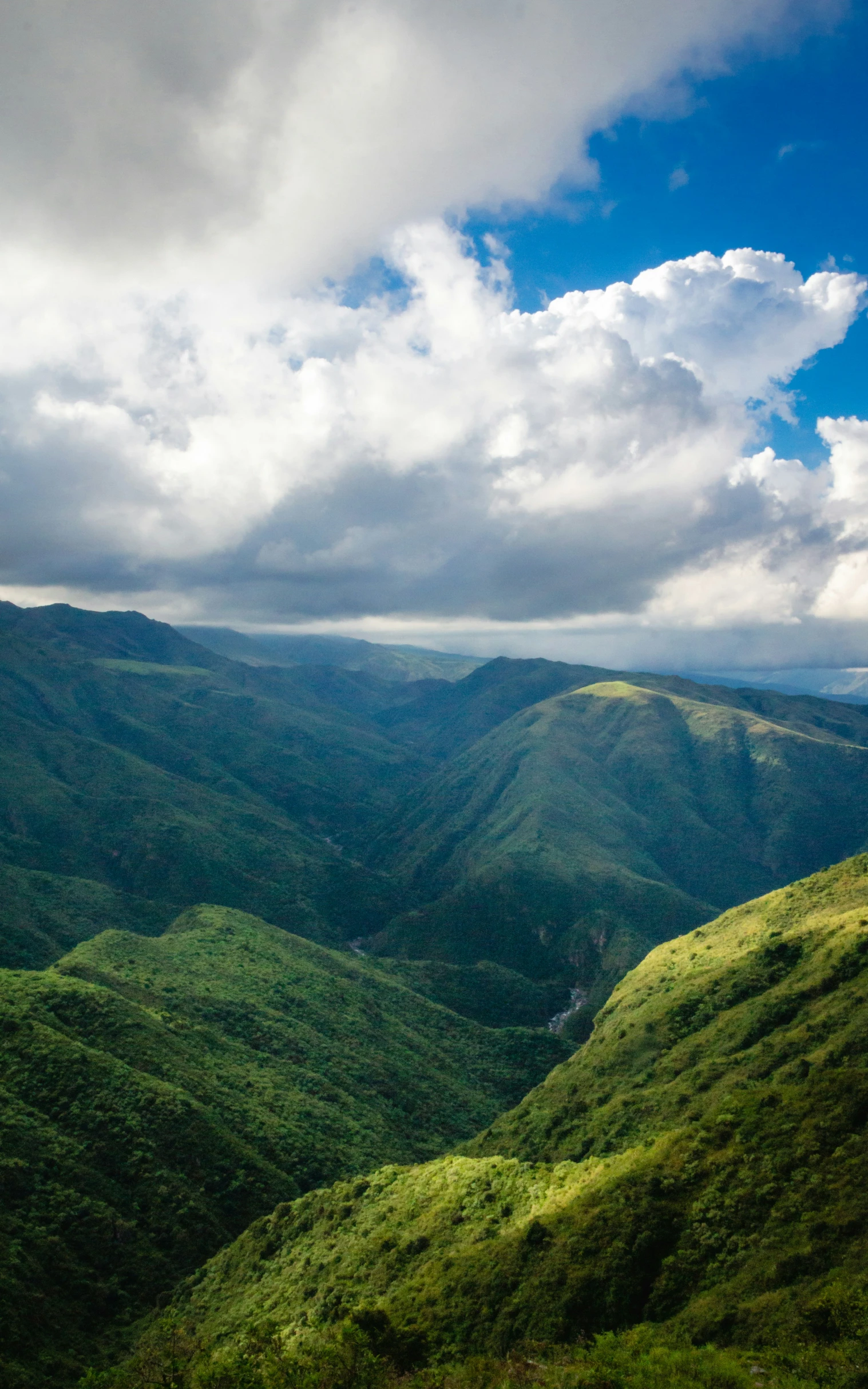 clouds and blue sky above a green mountains range