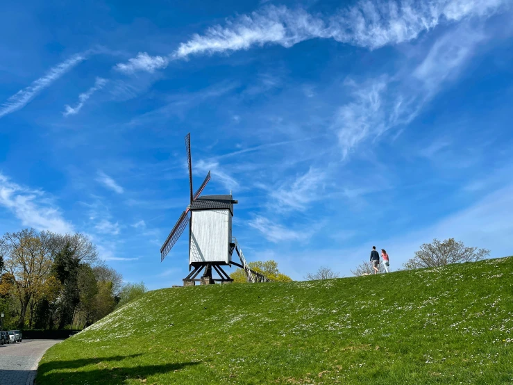 the people are by the windmill on the hill