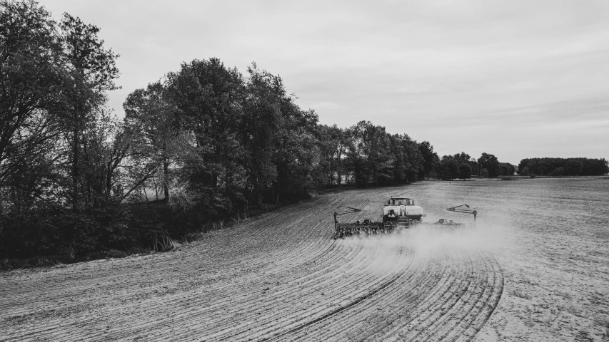 an tractor pulling it's trailer in the middle of a field