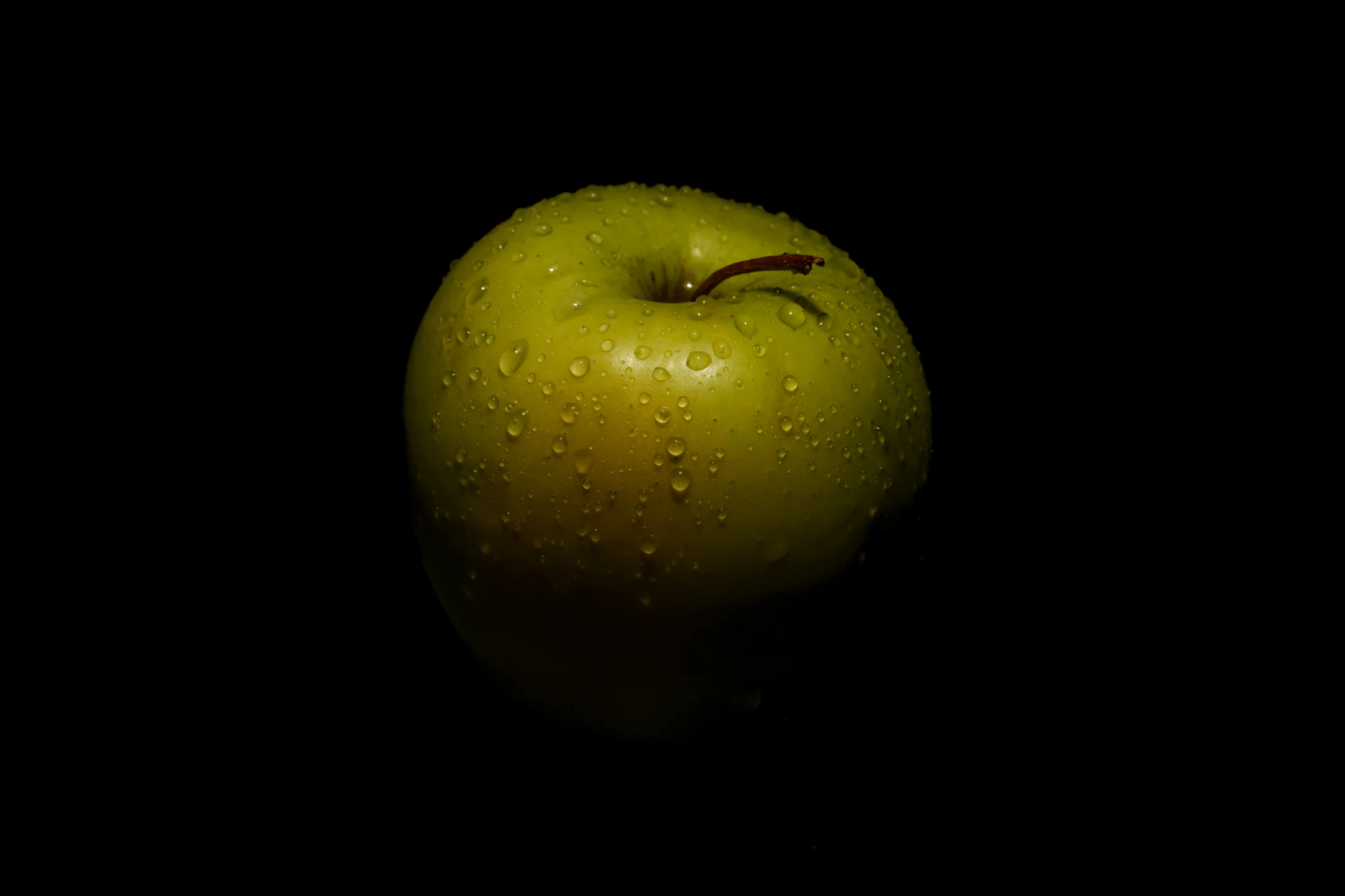 an apple in the dark with water drops
