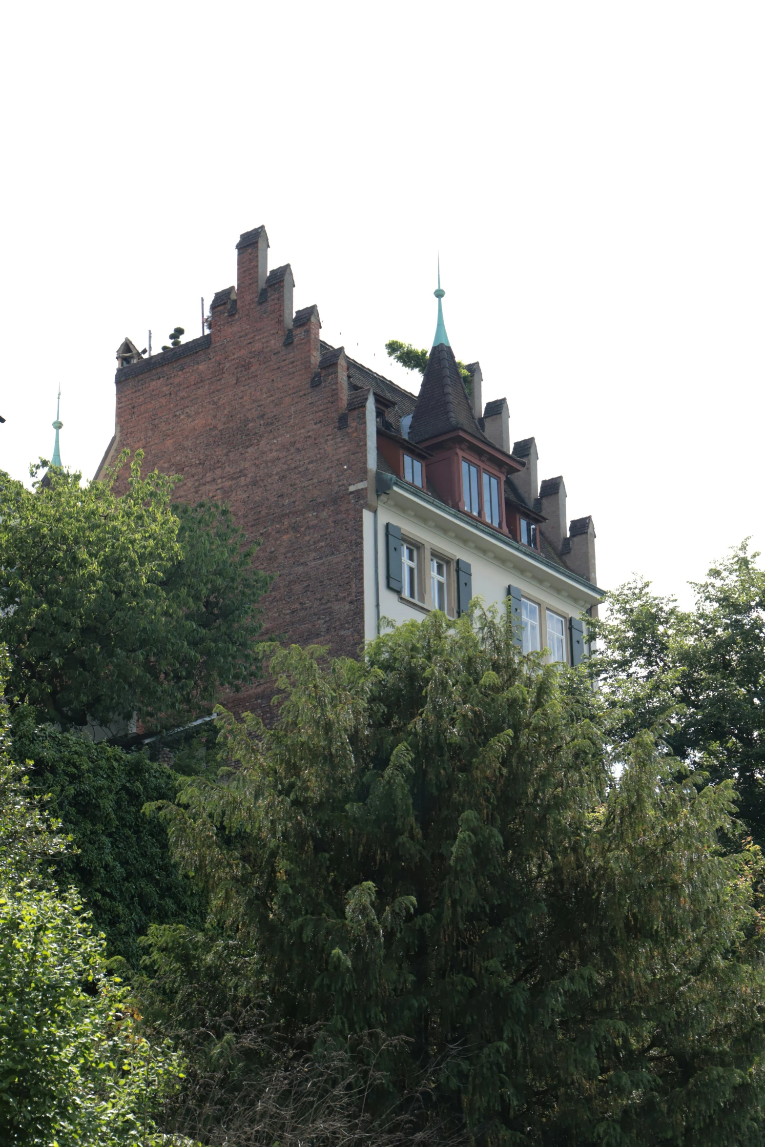 the top of an apartment building with a clock tower above a green area