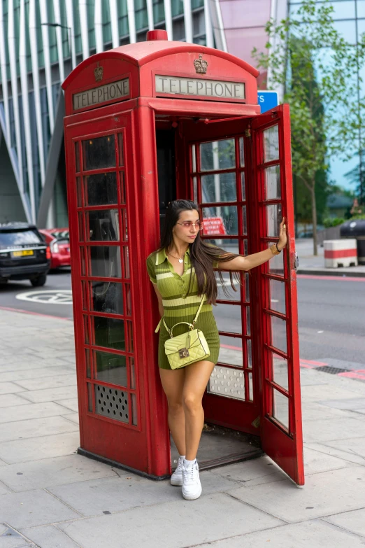 the woman stands at the door to the phone booth