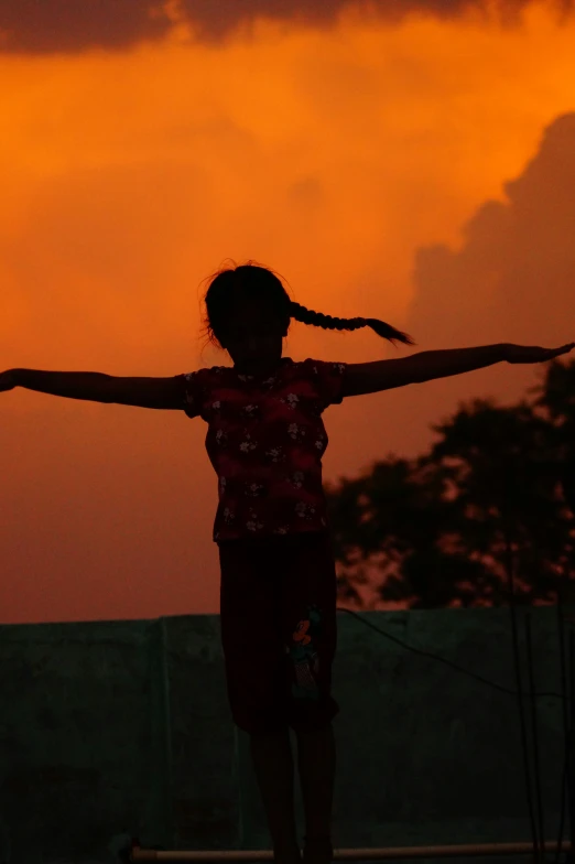 a woman holding onto the top of a skateboard in front of a sunset