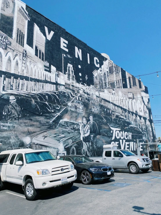 white suvs are parked outside a large mural