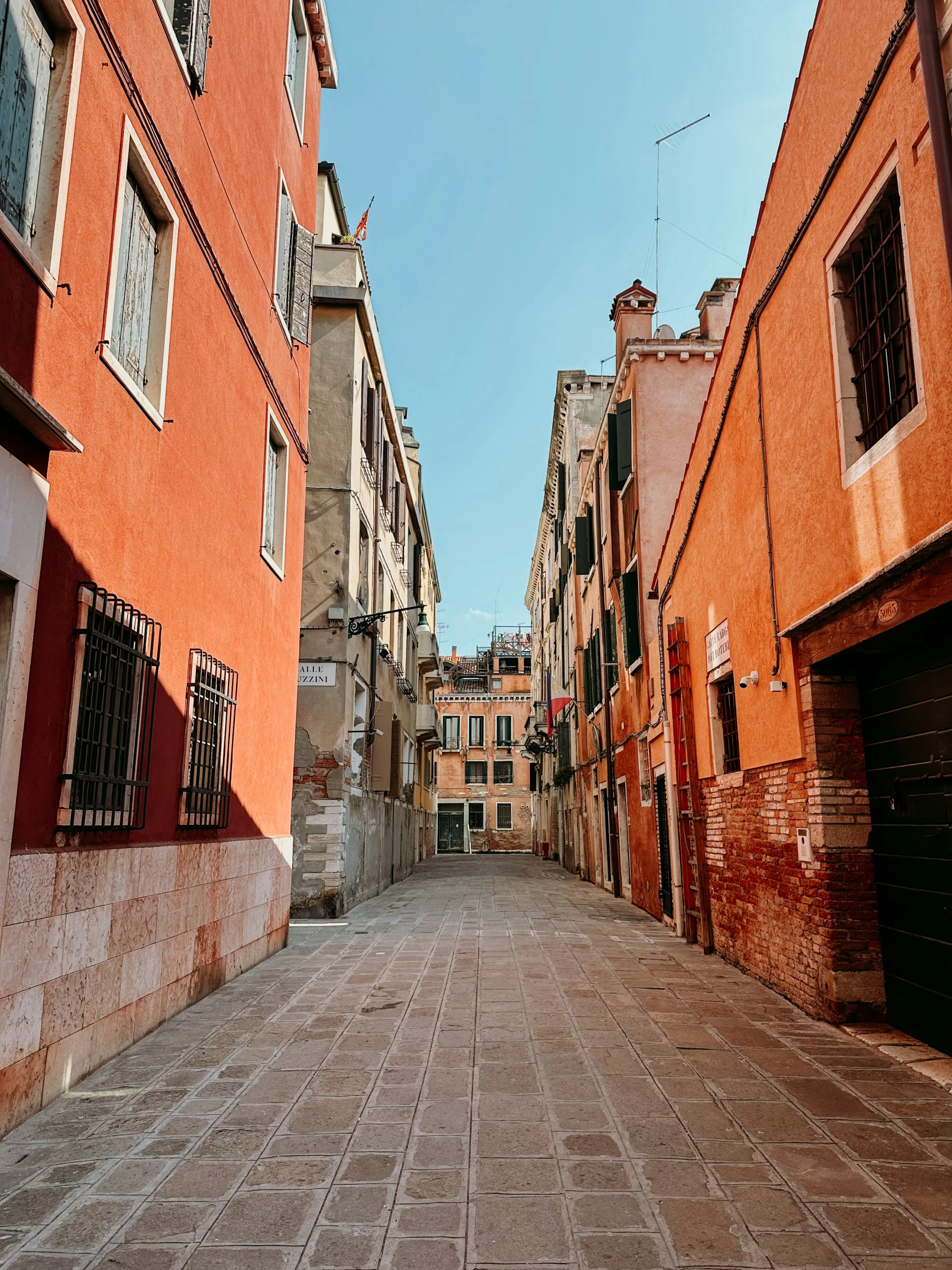 an old brick paved street with red shutters and a clock on the side