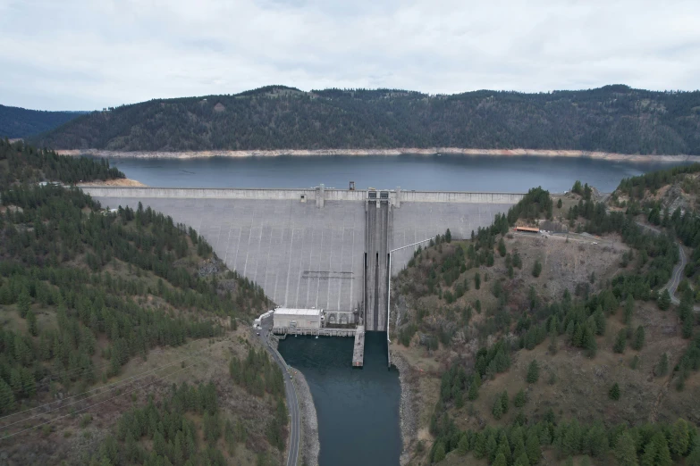 a dam with a body of water surrounded by forested land